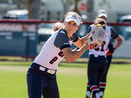 Female softball players on the field. One player is getting ready to pitch the ball.